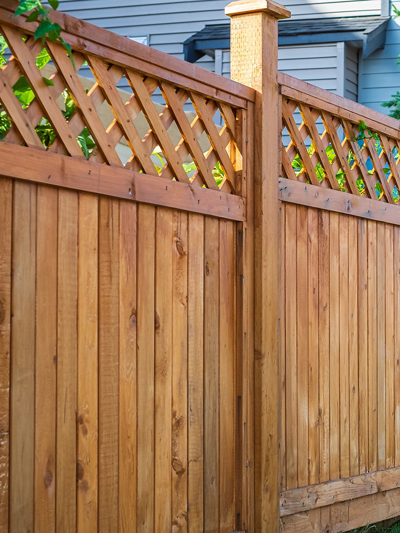 Nice new wooden fence around house. Wooden fence with green lawn. Street photo
